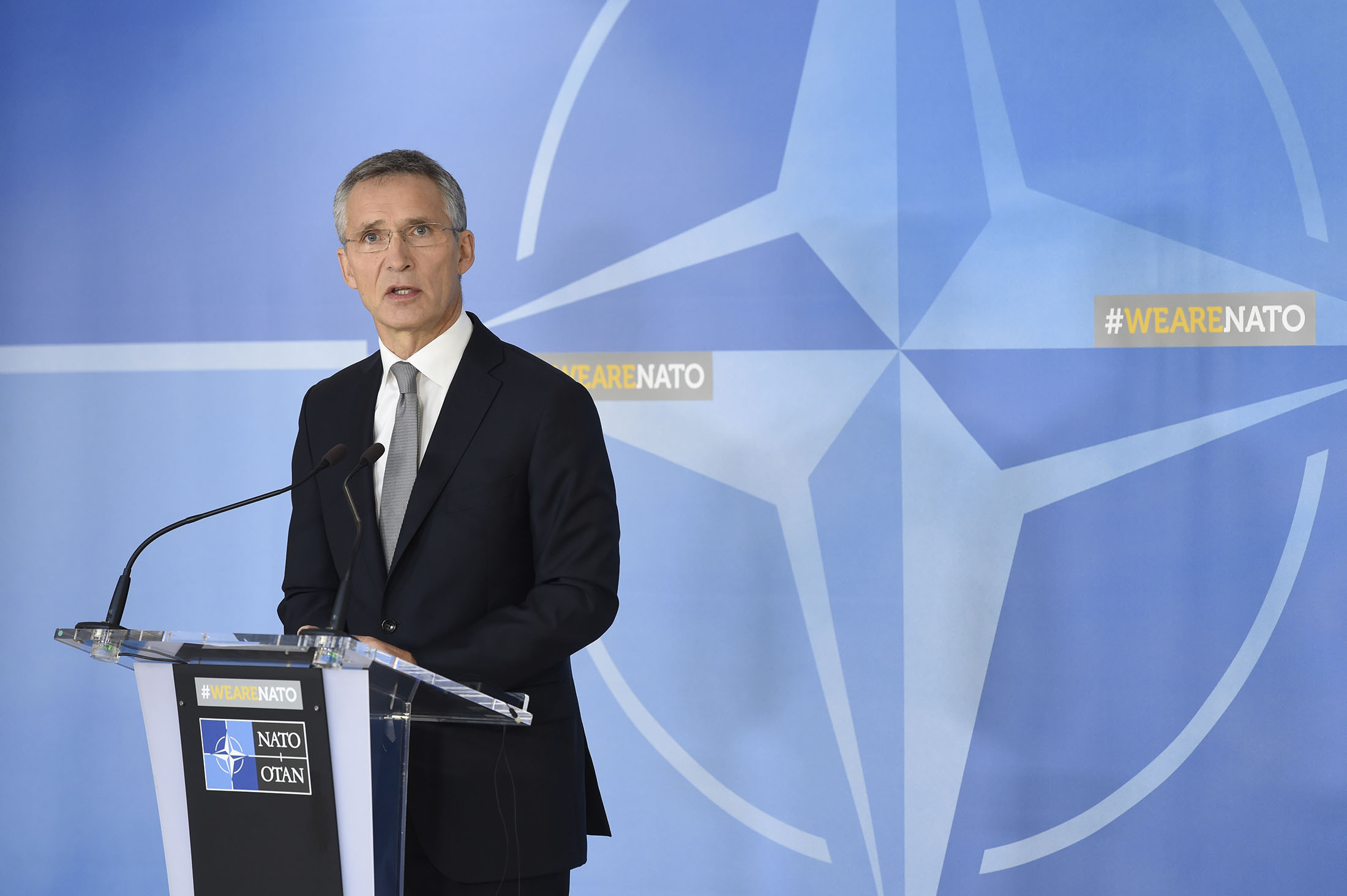 Jens Stoltenberg ved en talestol med NATOs logo i bakgrunnen