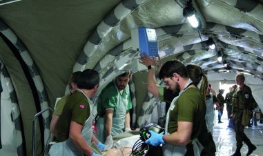 Soldater fra Forsvarets sanitet klargjør en pasient for røntgen i et feltsykehus under øvelse