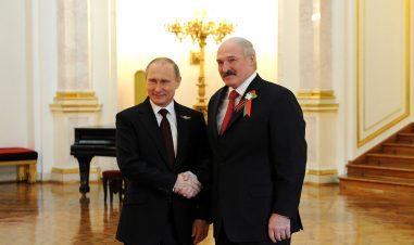 Putin og Lukasjenko står nære hverandre, og smiler under et håndtrykk.