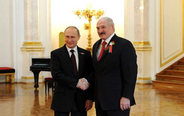 Putin og Lukasjenko står nære hverandre, og smiler under et håndtrykk.