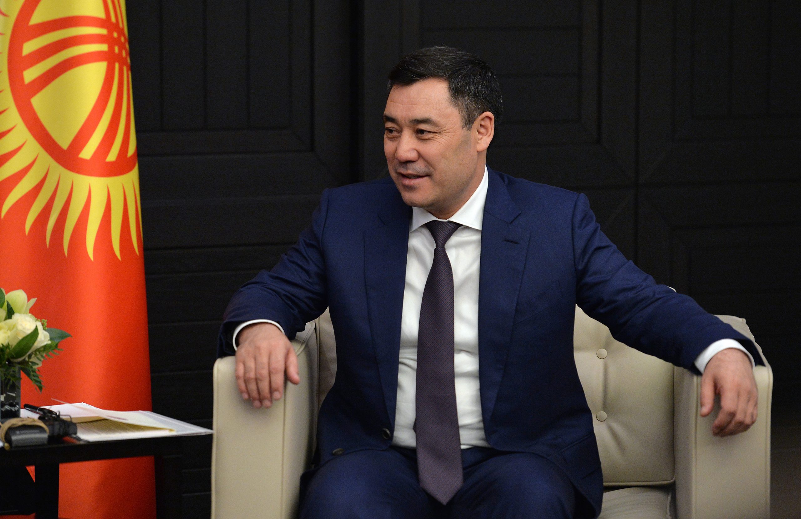 Japarov sitter i en lenestol foran det kirgisiske flagget