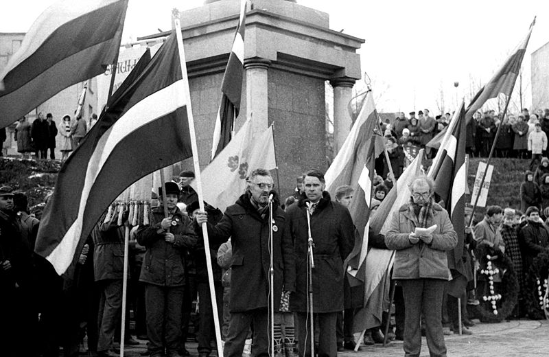 Mennesker samlet på en plass med det litauiske flagget. Noen snakker i en mikrofon