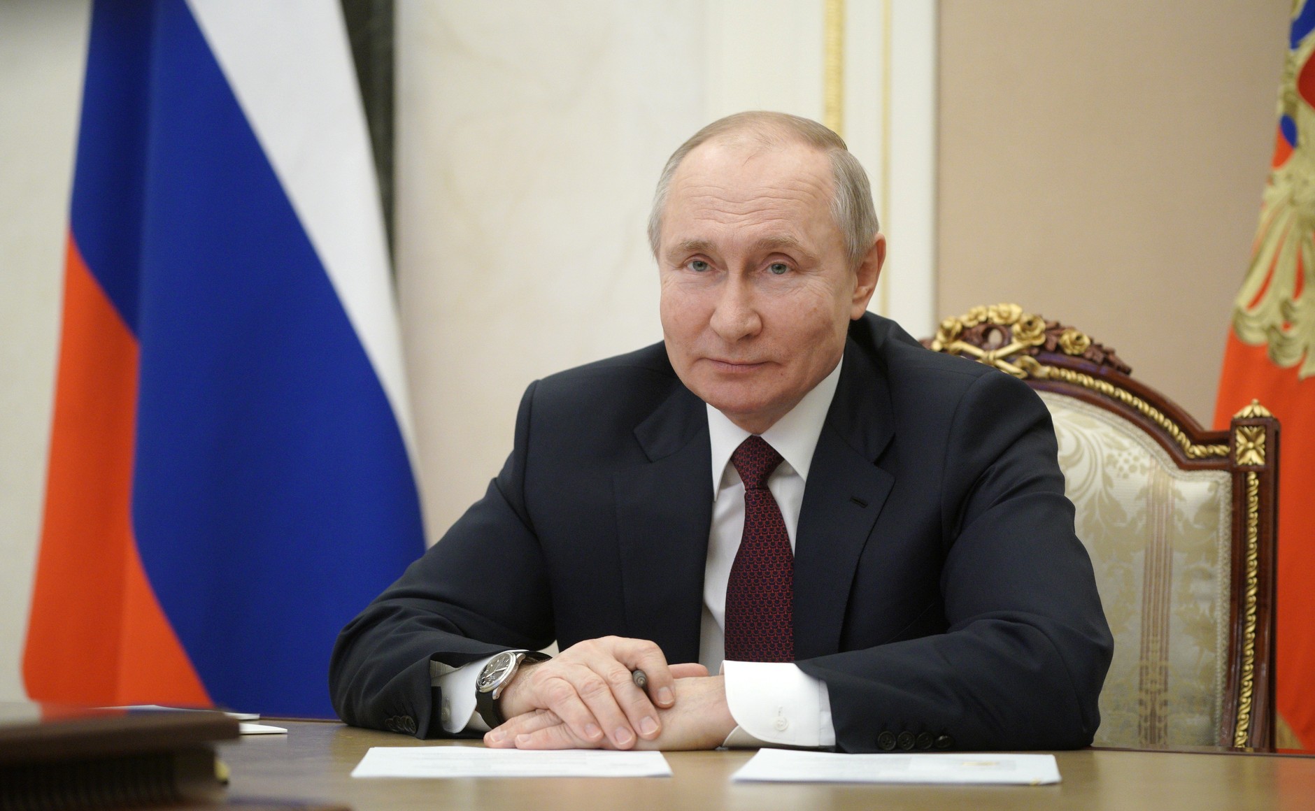 Putin sitter ved en pult med det russiske flagget bak seg.