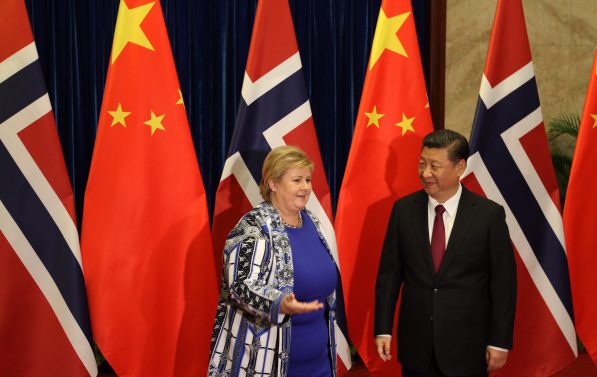 Solberg og Xi Jinping prater vennlig foran en rekke med norske og kinesiske flagg