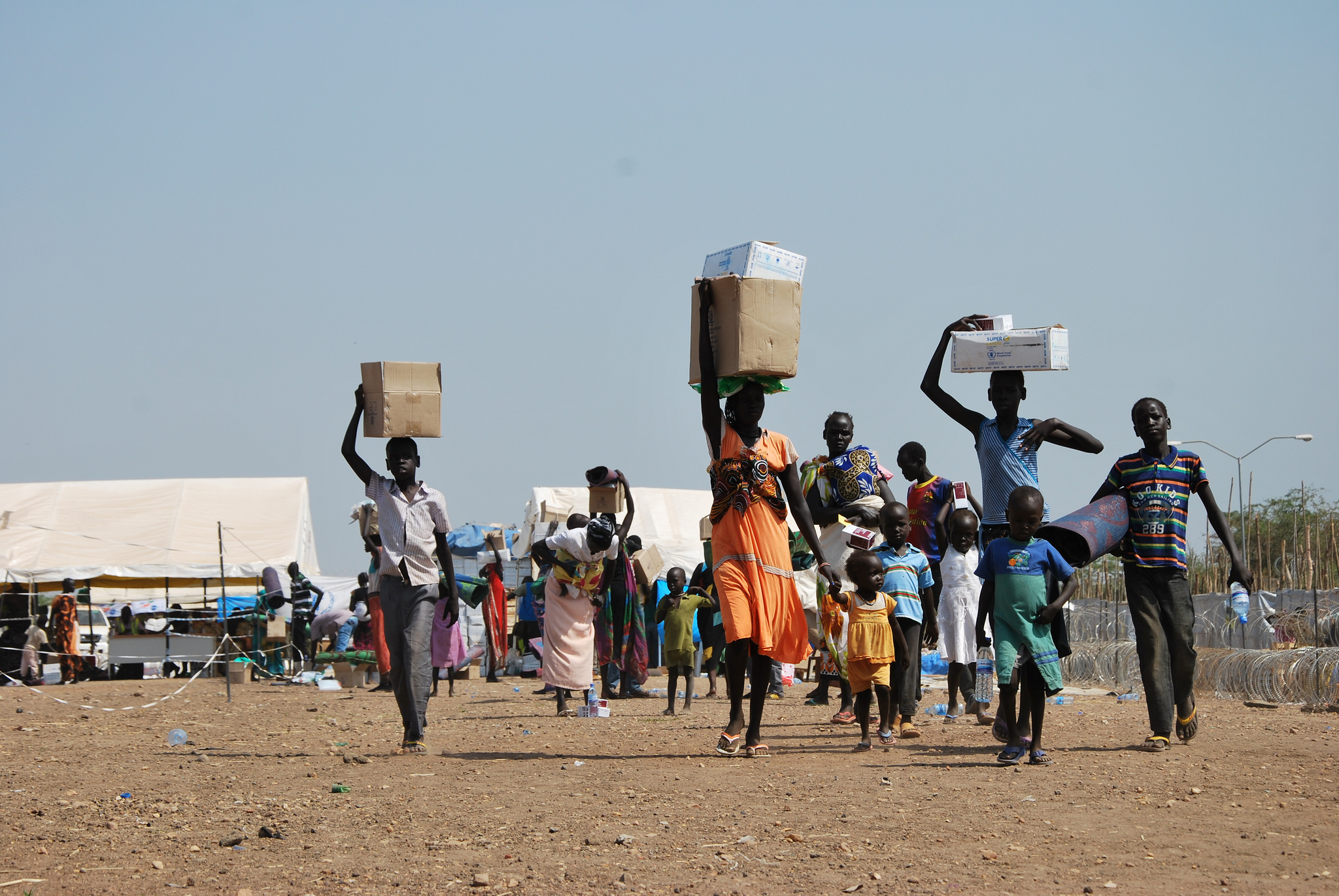 kvinner bærer vann og mat i en flyktningleir