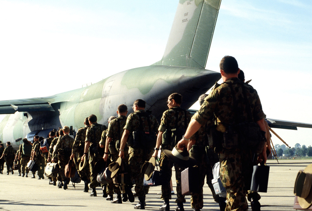 Soldater går på rekke inn i et militært fly