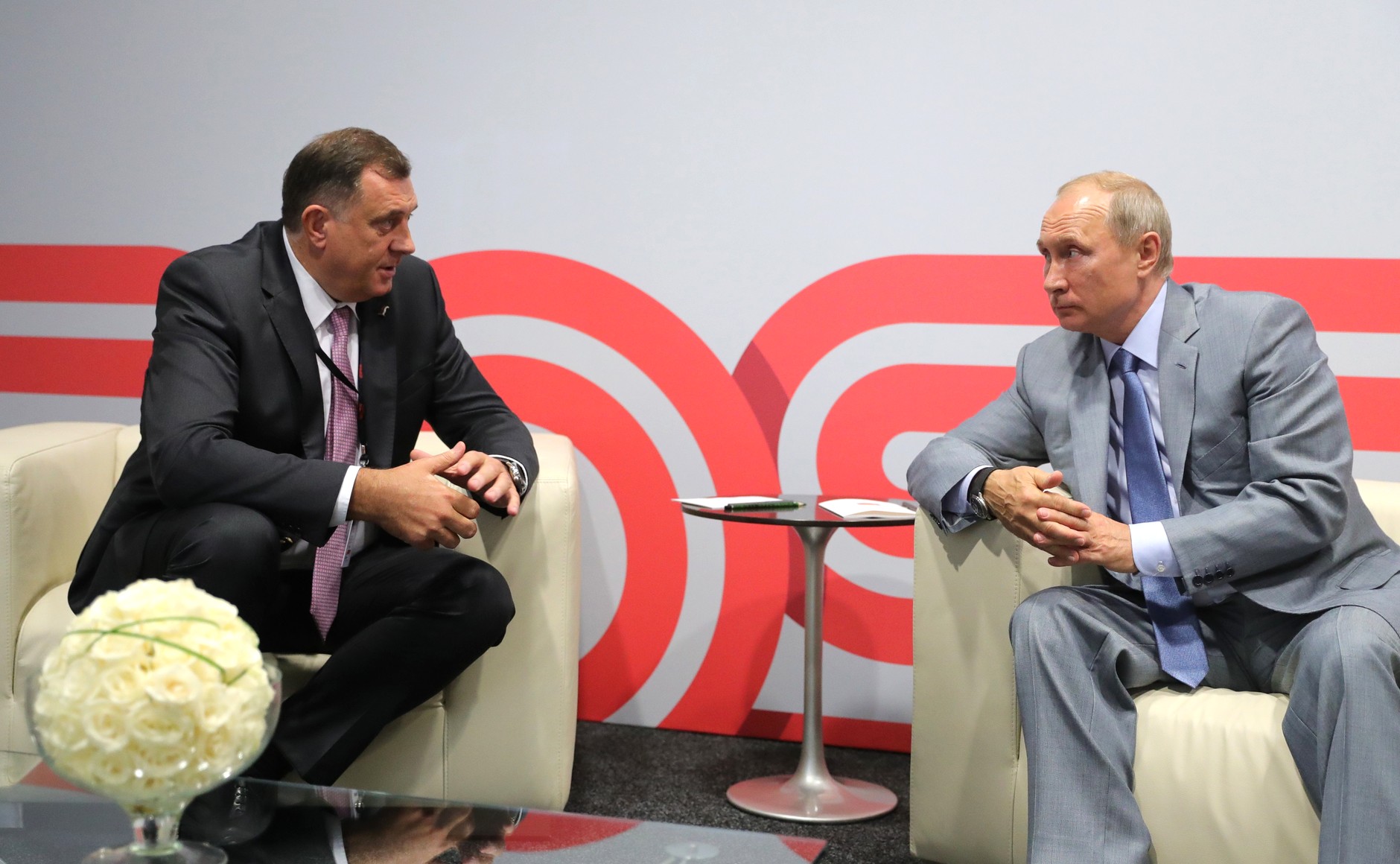 Milorad Dodik og Vladimir Putin sitter sammen og snakker foran et bord med blomster.