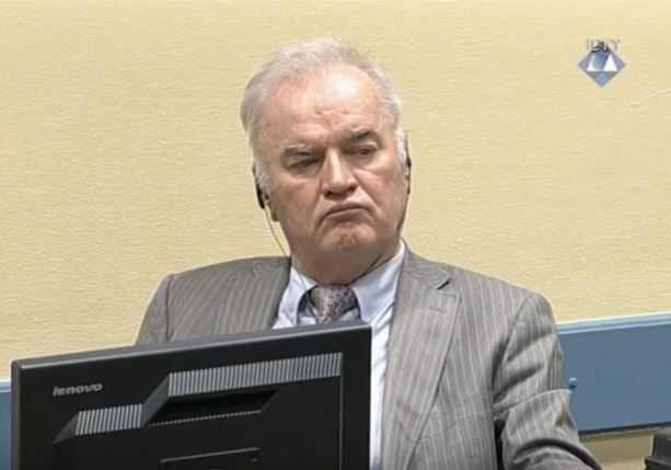 Ratko Mladic sitter med ryggen mot en gul vegg, med høretelefoner.
