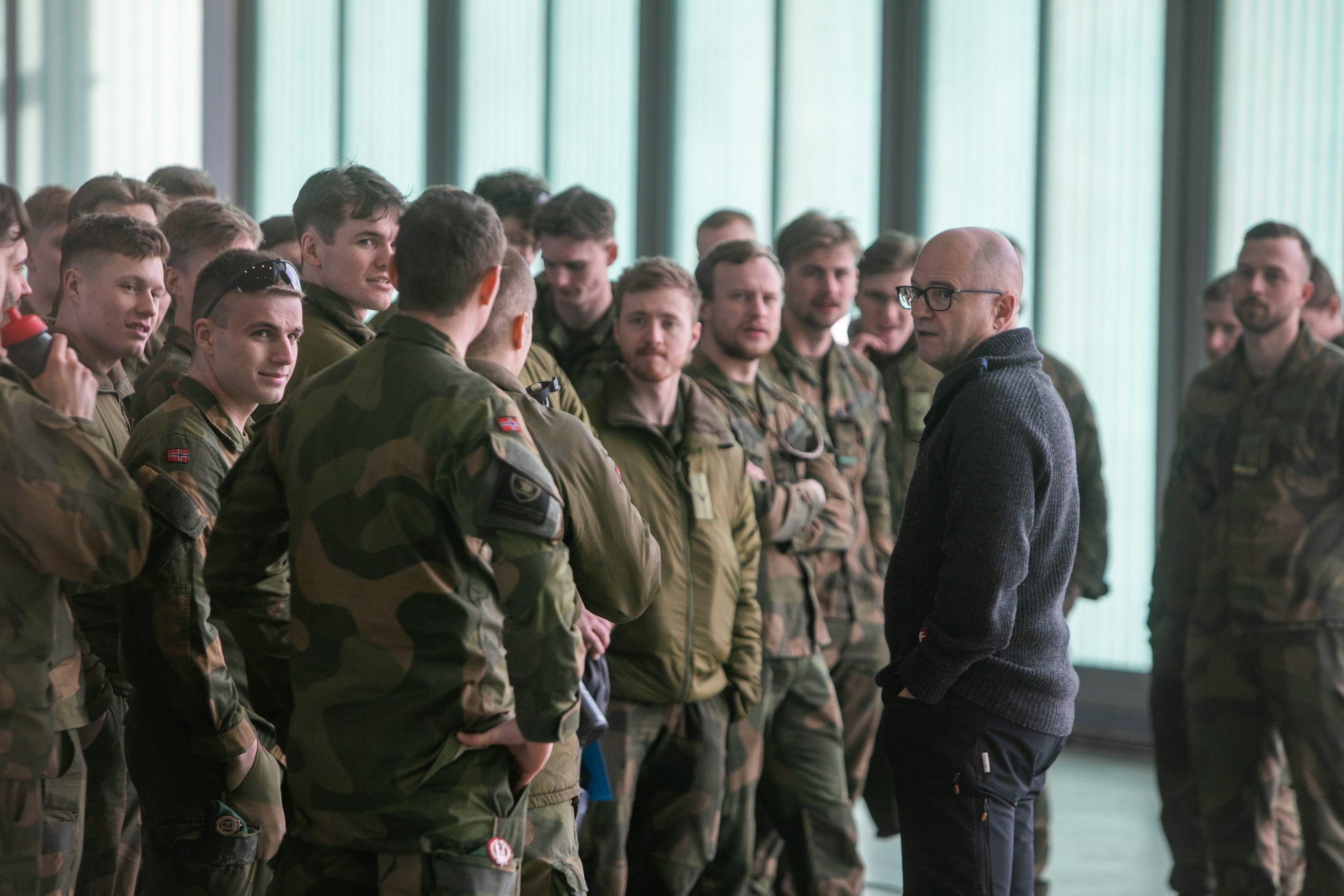 Forsvarsminister Odd Roger Enoksen står foran en gruppe militærkledde menn.