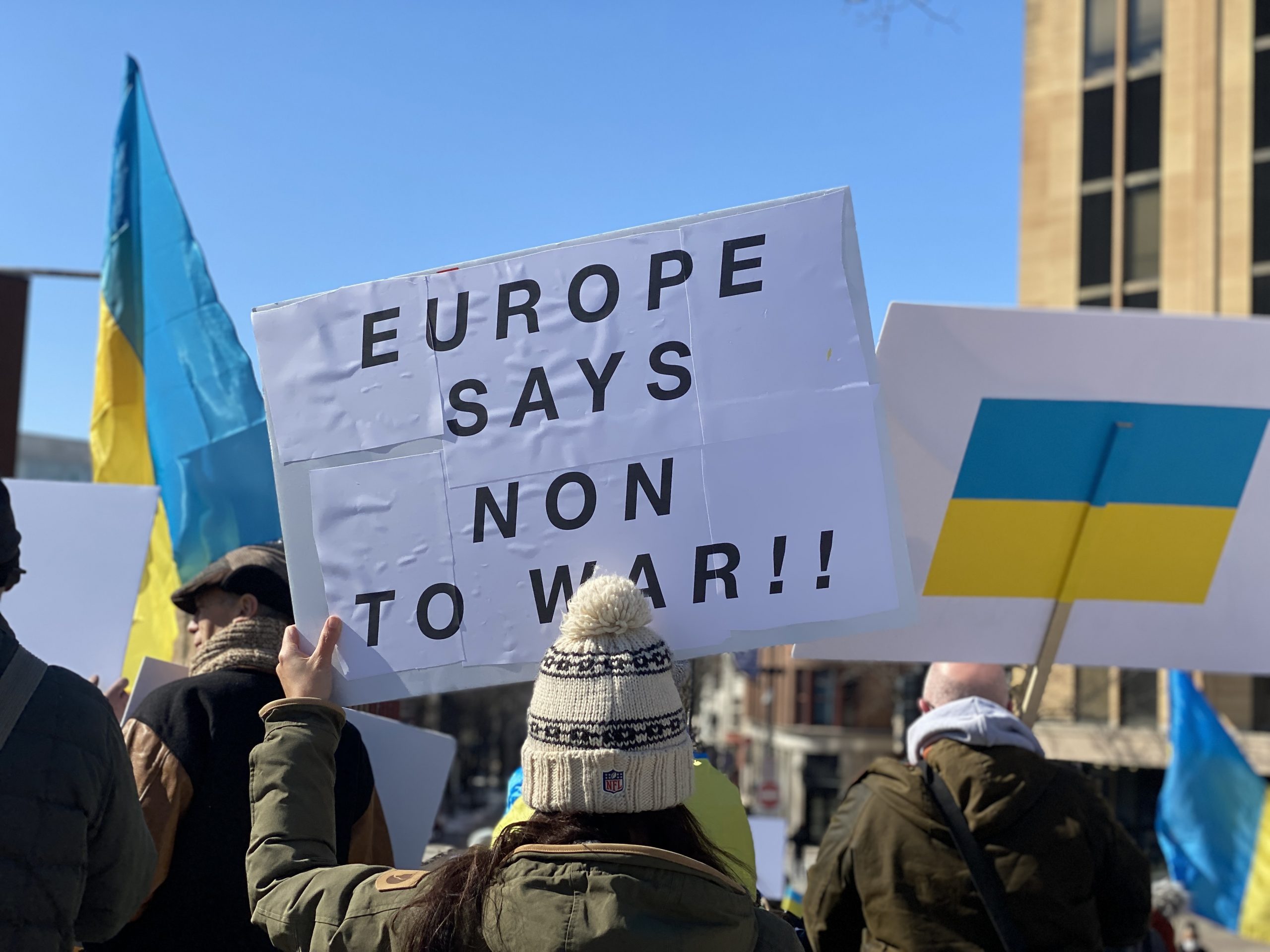 Mennesker i et demonstrasjonstog står med plakat der det står "Europa sier Nei til krig". Andre holder plakater med det ukrainske flagget.