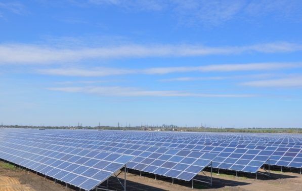 Bildet viser en solcellepark under blå himmel