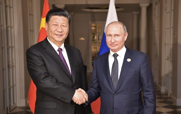 Russlands president Vladimir Putin og Kinas president Xi Jinping håndhilser for Kina og Russlands flagg.