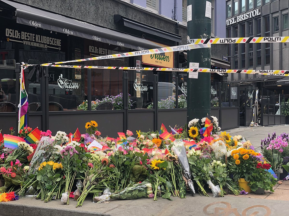 Bildet viser blomster sørgende la ned forran puben Herr Nilsen etter skytingen 25. juni i Oslo. Blant blomstene ligger det prideflagg. 