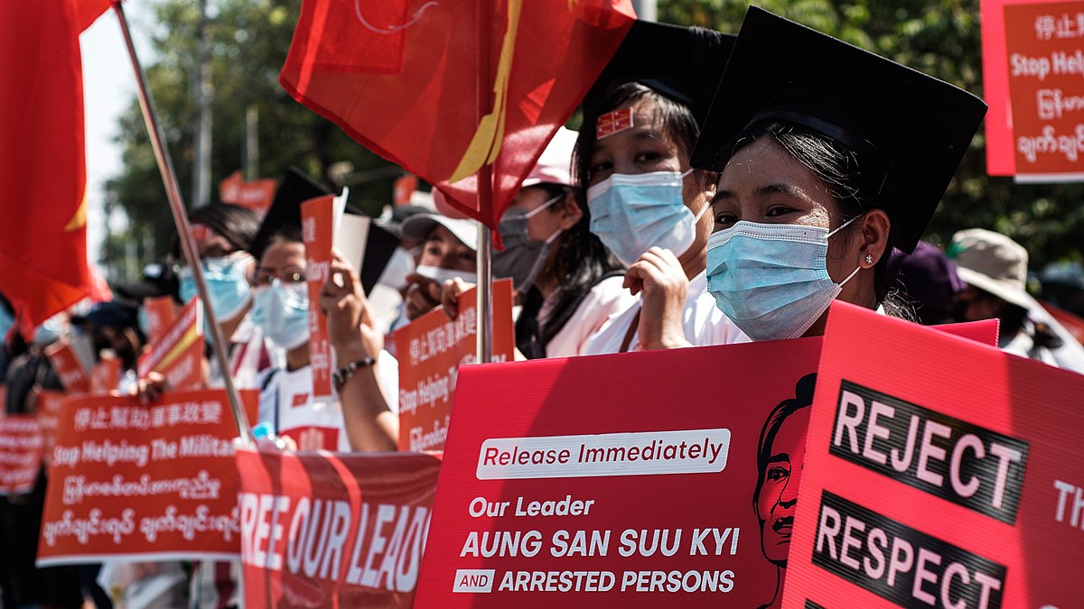 En kvinne står i protest og holder opp et skilt som ber om løslatelsen av Aung San Suu Kyi og andre arresterte personer.